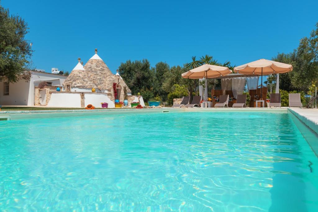 una piscina con agua azul y sombrillas en Trulli Olea with Pool, en San Vito dei Normanni