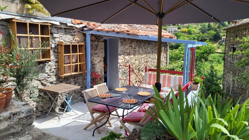 un patio con mesa, sillas y sombrilla en Gîtes chez Daniel "Cevennes 3", en Mars