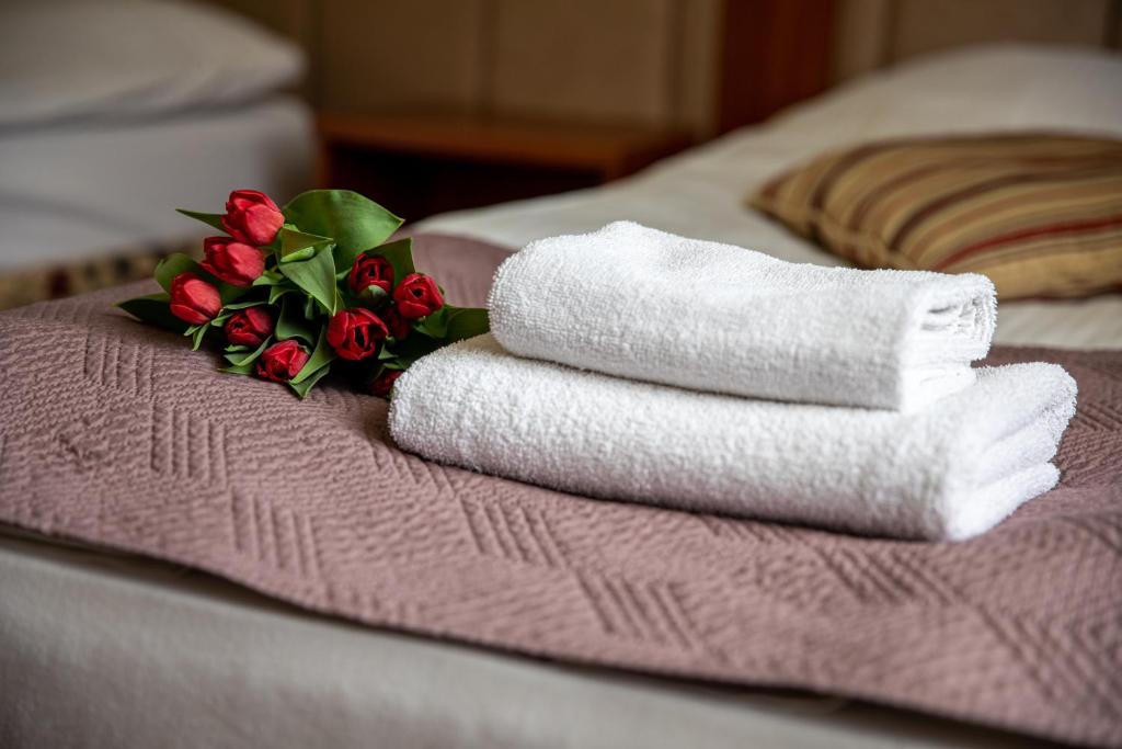 two towels and a bouquet of red roses on a bed at Hotel pod Wierzba in Świdnica