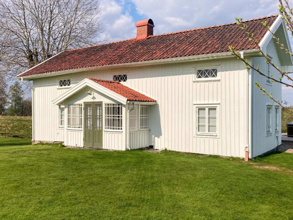ein weißes Haus mit einem roten Dach und einem Hof in der Unterkunft Holiday home ULRICEHAMN VII in Ulricehamn