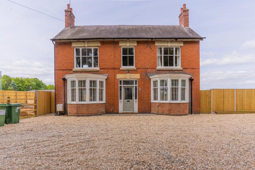 a red brick house with white windows and a fence at Felicity's House with Hot Tub! 