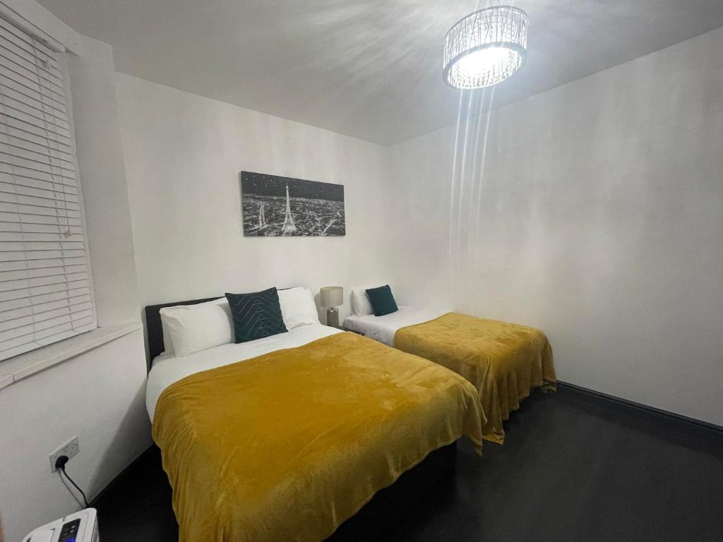 a bedroom with two beds with yellow sheets and a chandelier at Luxury Holiday Home in Manchester