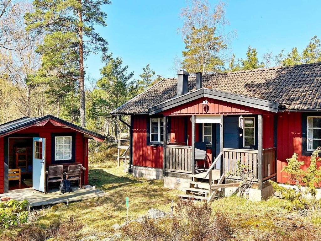 uma cabana vermelha na floresta com um alpendre em Holiday home ORNÖ II em Dalarö