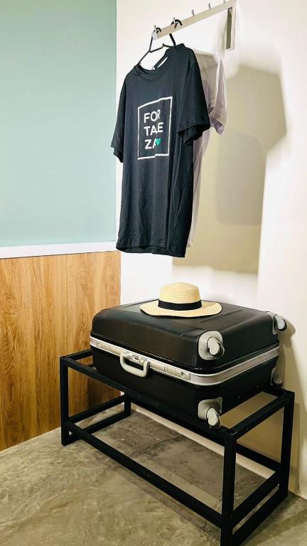 a tshirt and a suitcase on a shelf with a hat at URB Hotel in Fortaleza