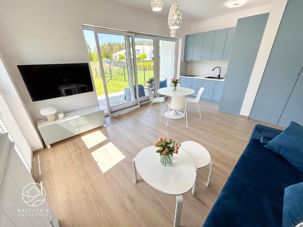 a living room with a couch and tables and a kitchen at Apartamenty Bałtyckie - Luxoro Park in Ustka
