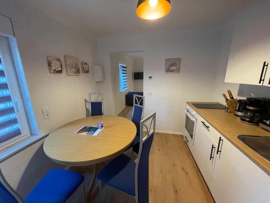 Apartment Mirabelle 3 في Püttlingen: مطبخ صغير مع طاولة خشبية وكراسي زرقاء