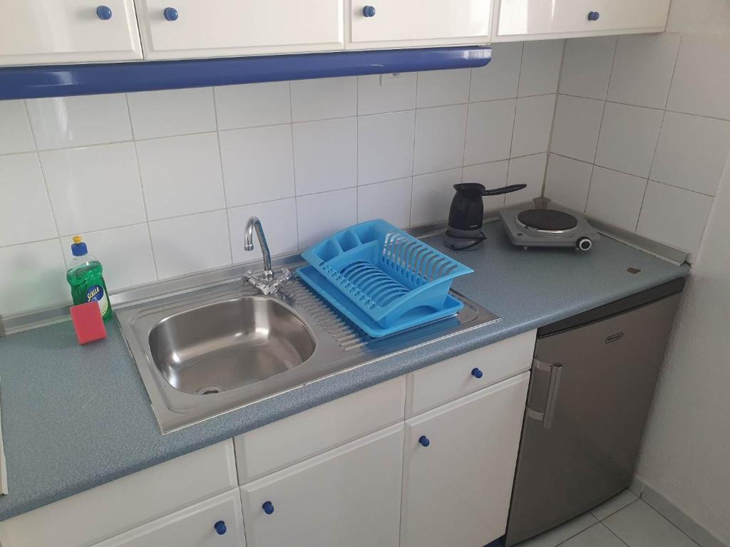 帕拉塔蒙Toula's Apartments的厨房水槽和蓝色的盘子旁边