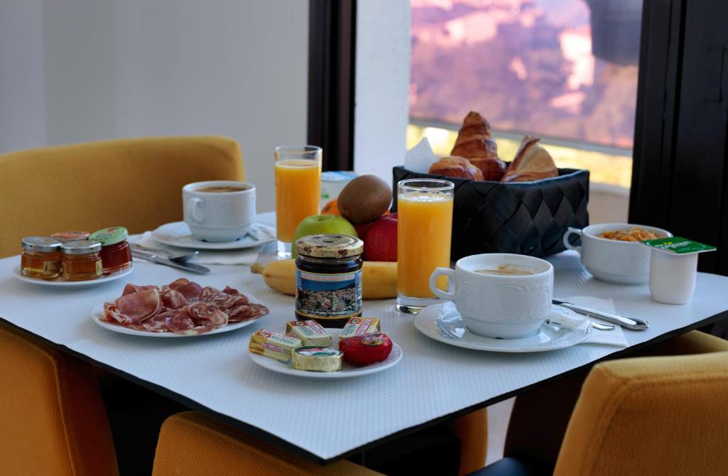 - une table de petit-déjeuner avec des aliments pour le petit-déjeuner et du jus d'orange dans l'établissement Hôtel Mare E Monti, à Piana