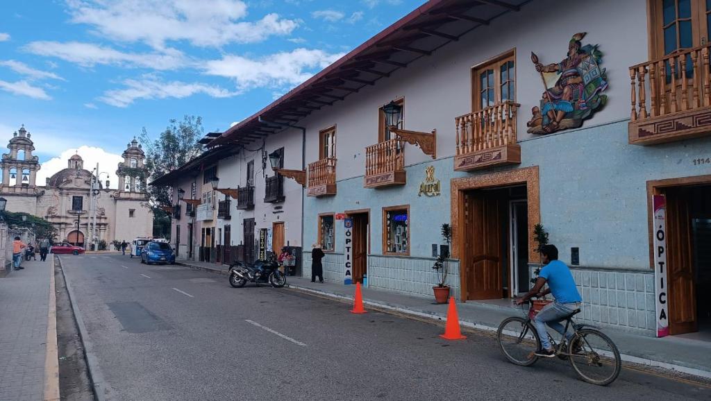 un hombre montando una bicicleta por una calle al lado de un edificio en Hotel Aural, en Cajamarca