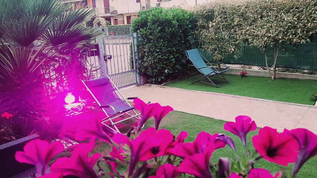 twee stoelen in een tuin met roze bloemen bij Appartamento in Cigole