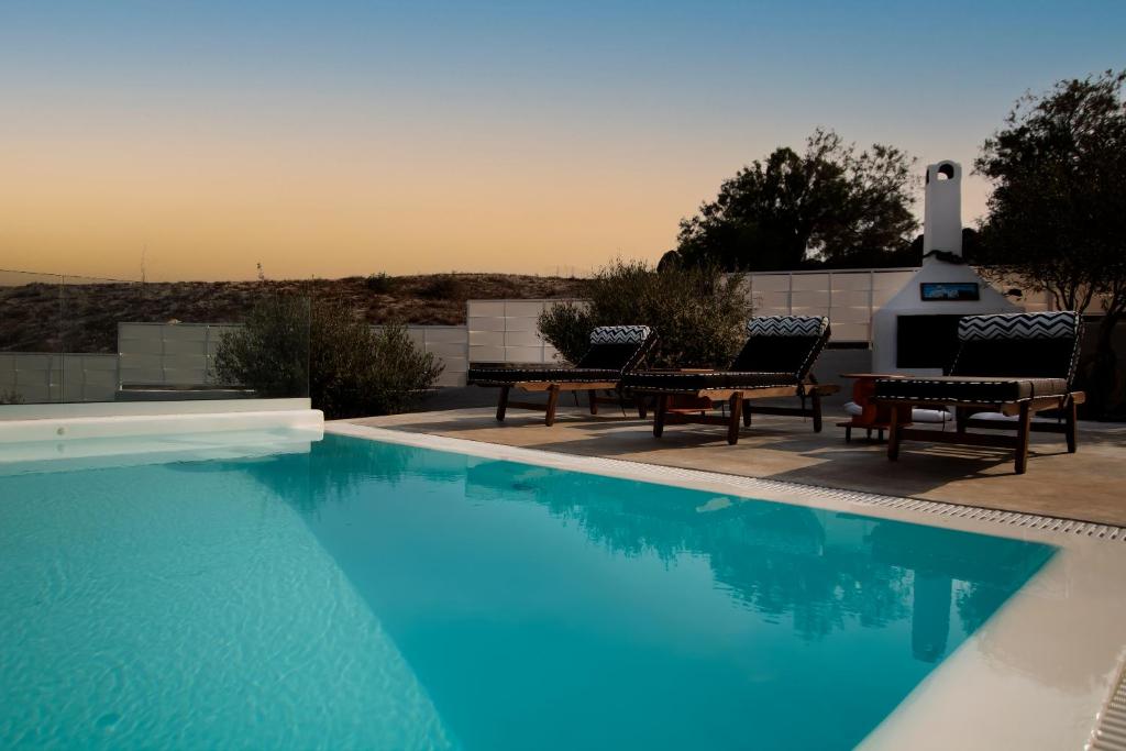 a swimming pool with two chairs and a table at Sorocada Private House in Akrotiri
