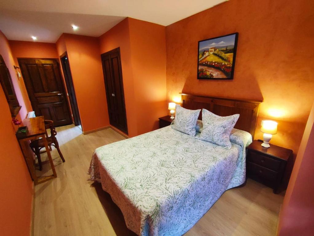 a bedroom with a bed with orange walls at Hotel Rural Pajarapinta in Molinaseca