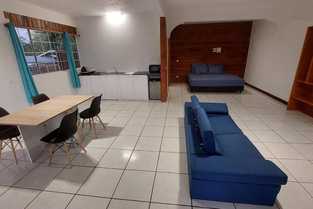 - un salon avec un canapé bleu et une table dans l'établissement Moorea Maharepa Appartement, à Paraoro