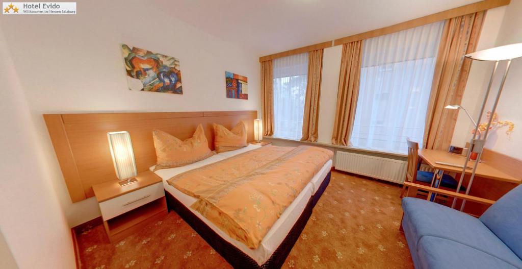 1 dormitorio con 1 cama y 1 sofá azul en Hotel Evido Salzburg City Center en Salzburgo