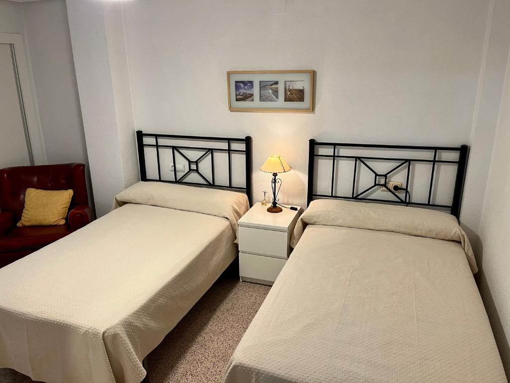 sypialnia z dwoma łóżkami i lampą na stole w obiekcie Alquileres Morasol - RECIÉN REFORMADO ZONA CENTRO w mieście Santa Pola