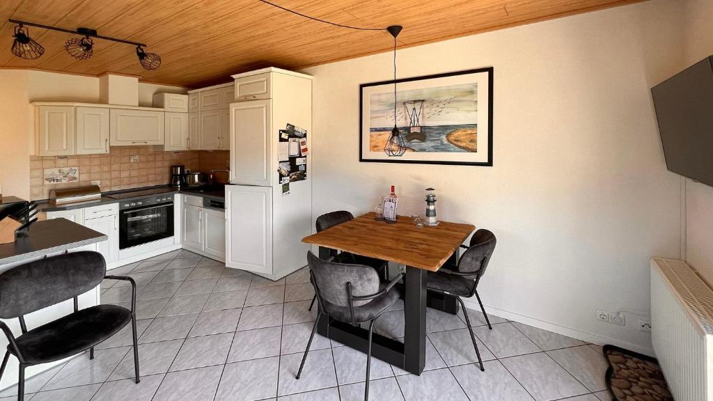 eine Küche mit einem Holztisch und schwarzen Stühlen in der Unterkunft Ferienwohnung am Sonnenstrahl in Dorum Neufeld