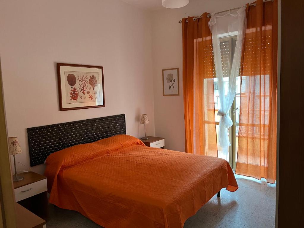 a bedroom with a bed with an orange blanket and a window at La Casa del Professore in Nicotera Marina