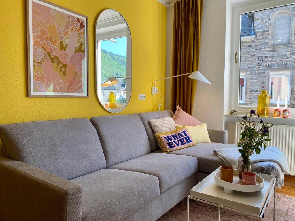 a living room with a gray couch and yellow walls at Stück vom Glück in Enkirch