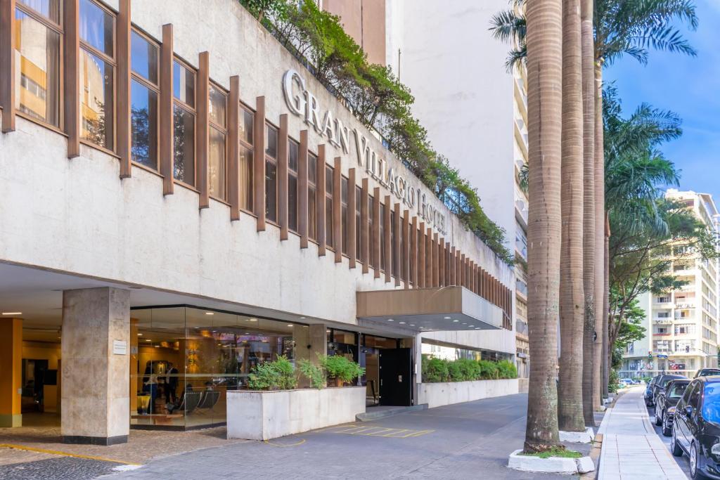 a building with a palm tree in front of it at Gran Villagio Hotel SP by Castelo Itaipava in Sao Paulo