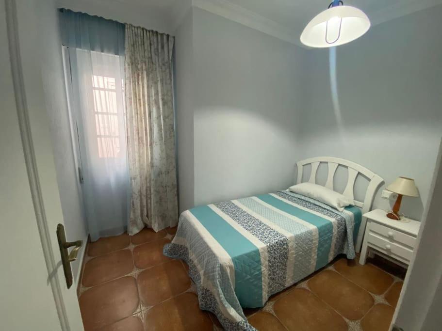 a small bedroom with a bed and a window at Casa Tagoror in Punta Umbría