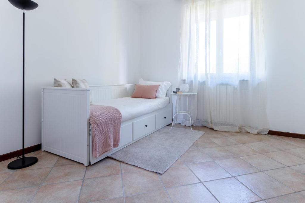 Dormitorio blanco con cama con manta rosa en Profumodilago, en Angera