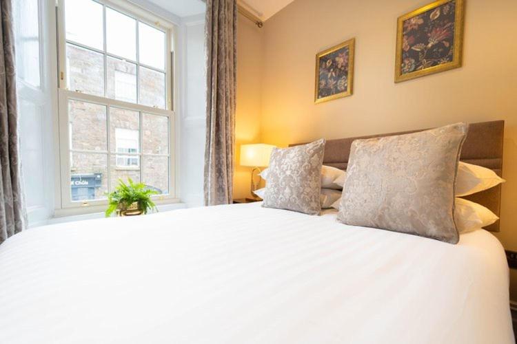 a bedroom with a large white bed with a window at Adams Townhouse in Dingle