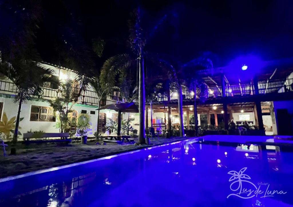 a swimming pool in front of a building at night at Hostal Luz de Luna in Palomino