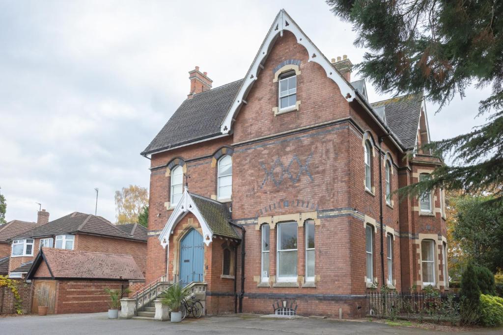 an old brick building with a blue door at Two Elegant Victorian Apartments 1BR & 2BR in Cheltenham, Cotswolds - Sleeps 10 - FREE Parking in Cheltenham