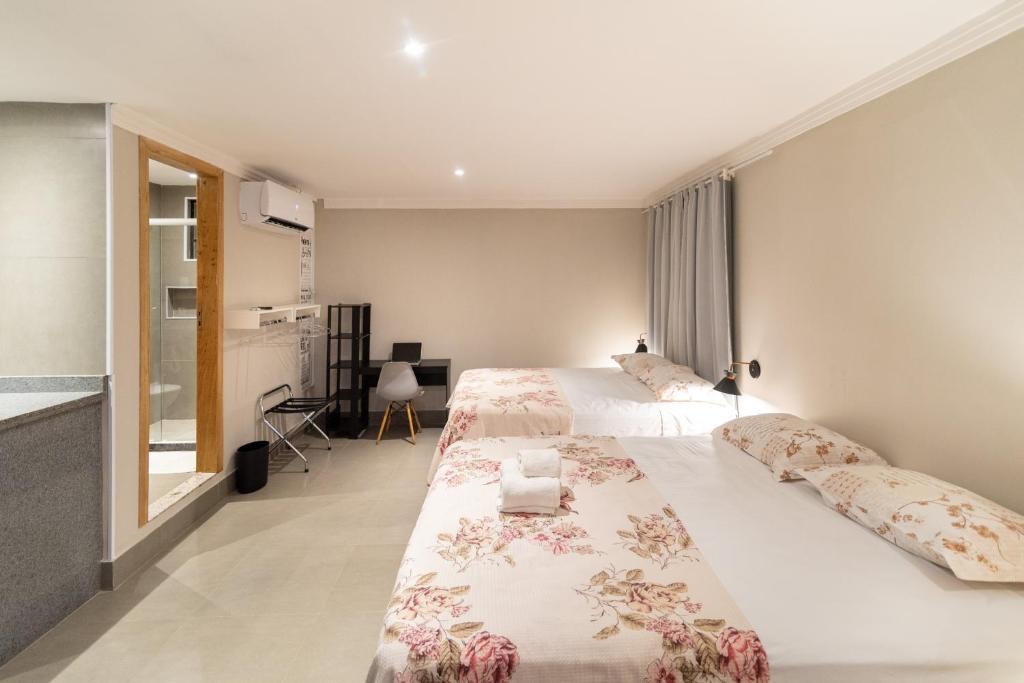 a large bedroom with two beds and a desk at HMG Rio Suítes in Rio de Janeiro