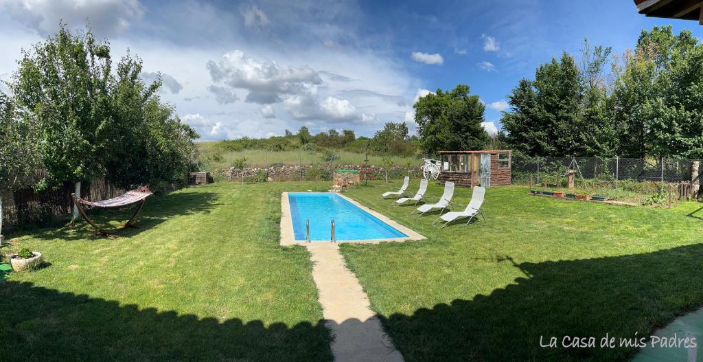 un patio trasero con piscina y parque infantil en La Casa de mis Padres, en Rabanales