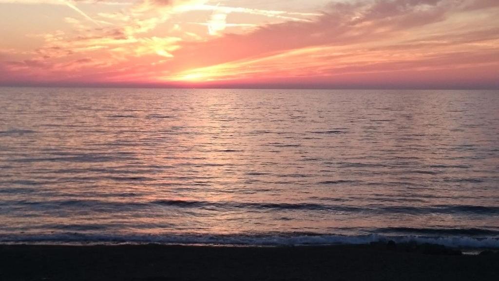 una puesta de sol sobre el océano en la playa en Maritsa's Roses Apartments en Pomos