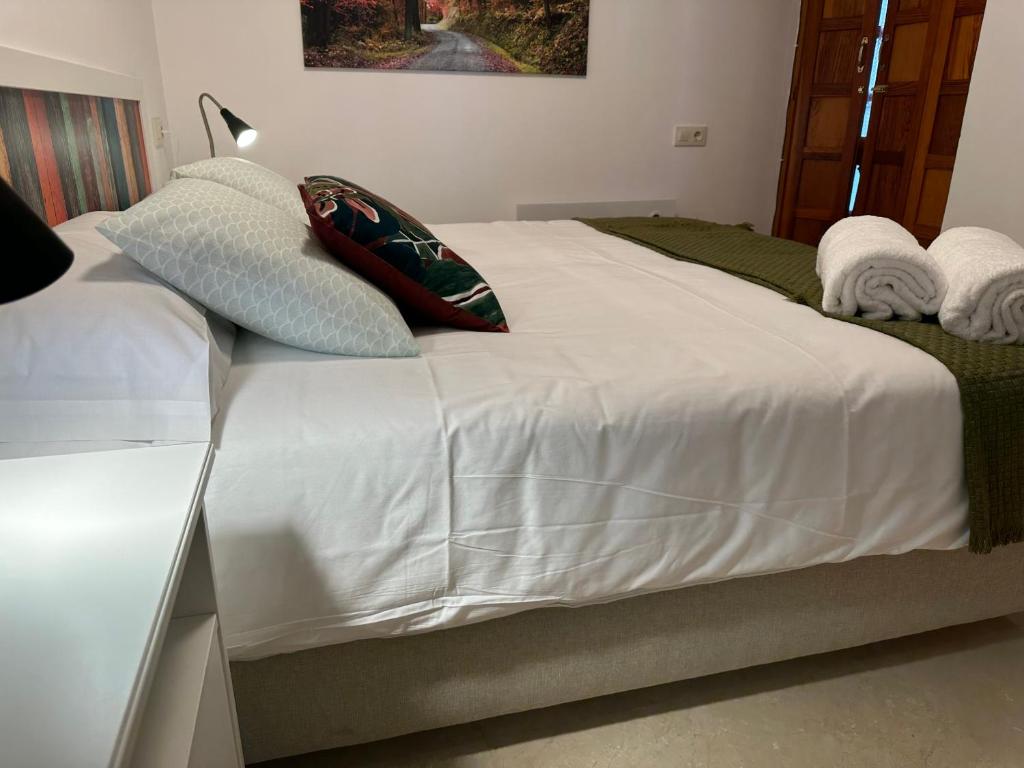 ein weißes Bett mit zwei Kissen darüber in der Unterkunft Porta da Vila by Oktheway in Puentedeume