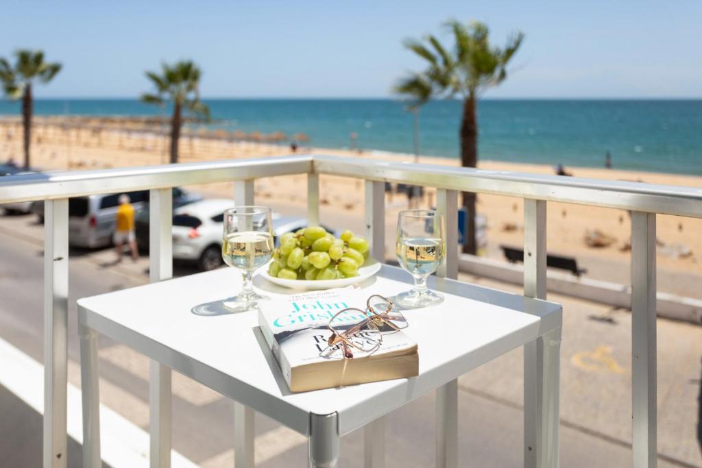 una mesa con una bandeja de fruta y copas de vino en la playa en Stunning Studio with Beach Front- Astro Quarteira by Centralgarve, en Quarteira