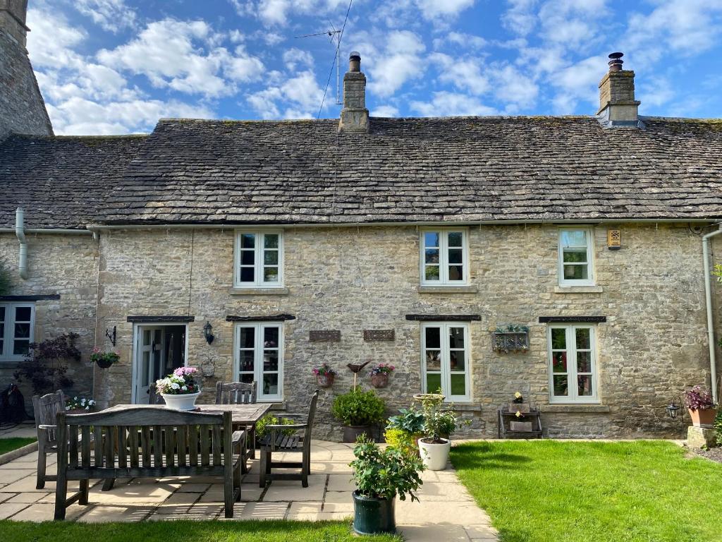 an old stone house with a table and chairs at Newmans Cottage in Burford
