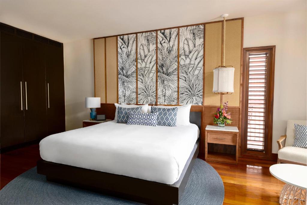 King bed with white linens, patterned headboard, wooden nightstands, and dark wardrobe in spacious suite.