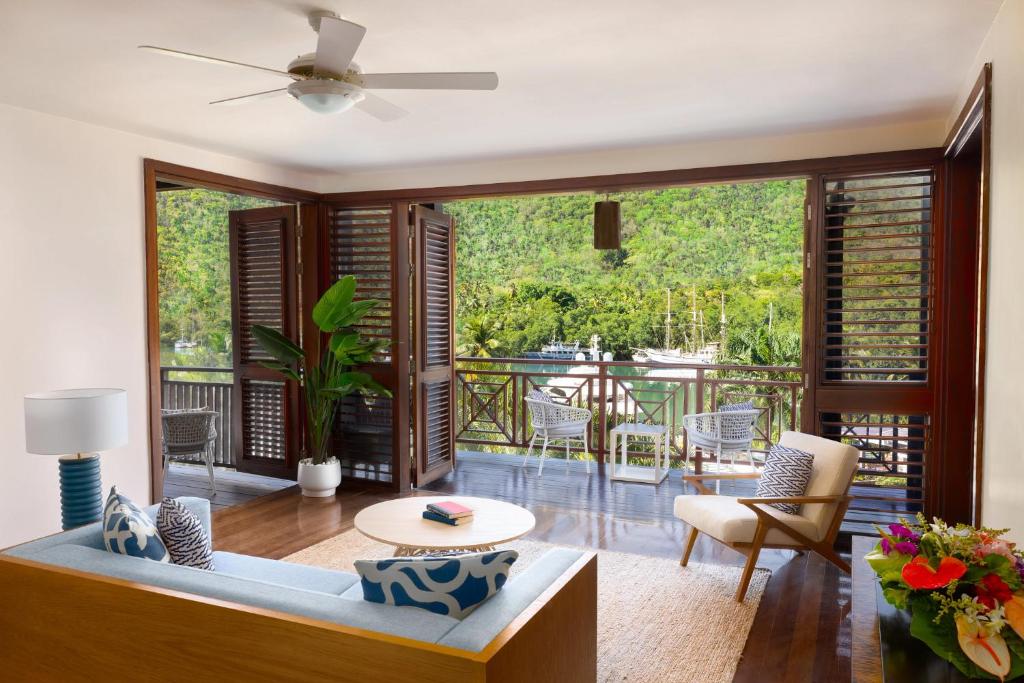 Suite interior with open doors revealing balcony overlooking dense green forest vegetation.