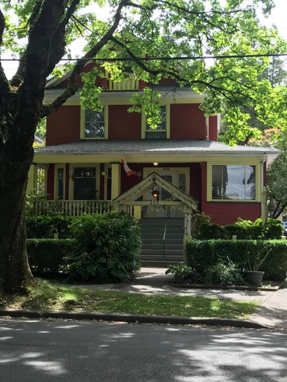 uma casa vermelha com uma árvore em frente em Douglas Guest House em Vancouver