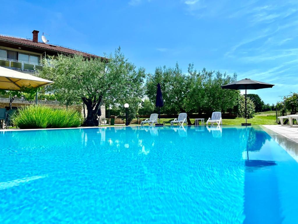ein großer blauer Pool mit Stühlen und einem Sonnenschirm in der Unterkunft Pansion Villa Margerita in Poreč