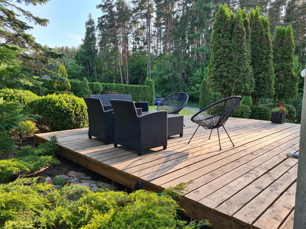 una terraza de madera con sillas y sillas. en GREEN HOUSE, en Anykščiai
