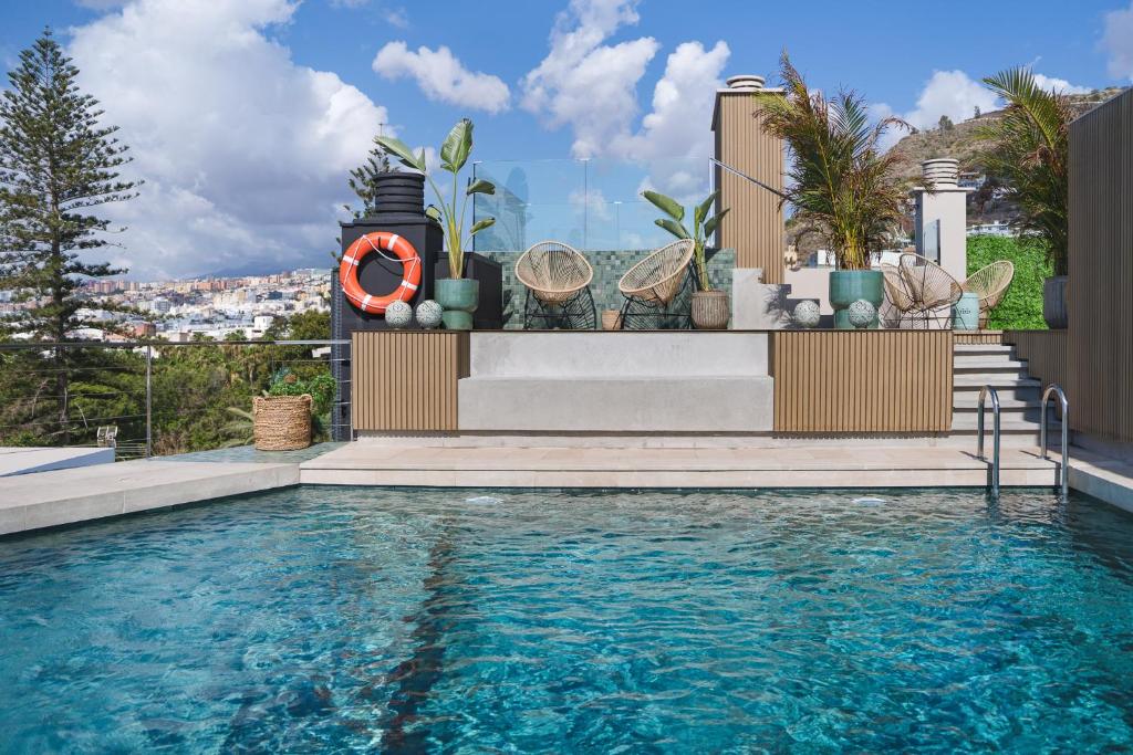 a swimming pool with a clock on the side of a house at Hotel Taburiente S.C.Tenerife in Santa Cruz de Tenerife