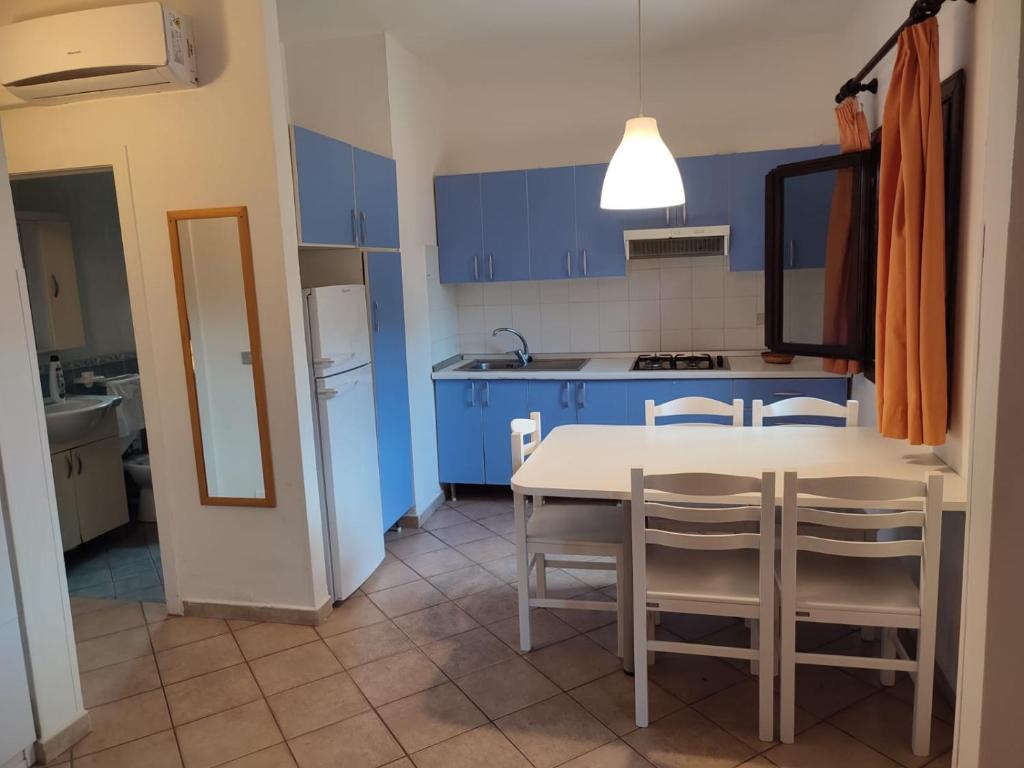 a kitchen with blue cabinets and a white table and chairs at KAMARINA RESORT in Scoglitti