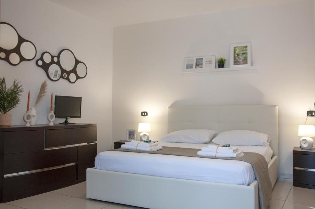 1 Schlafzimmer mit einem weißen Bett und einem TV in der Unterkunft Le Muse in Caserta