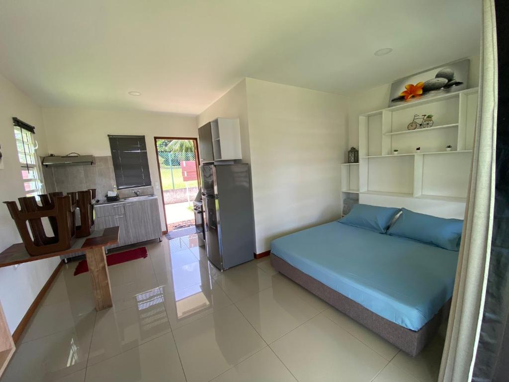 a small bedroom with a blue bed and a kitchen at Jorsen House Tahiti 2 : bungalow confortable in Taravao