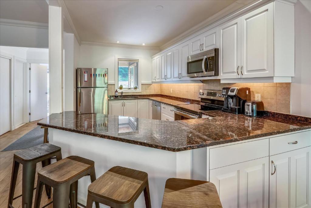 a kitchen with white cabinets and a granite counter top at Topnotch Retreat in Stowe