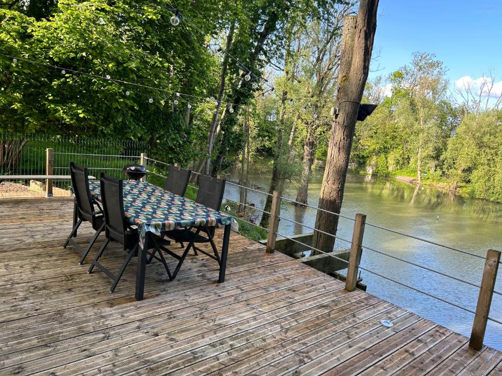 a table and chairs on a wooden deck next to a river at Ô Chalet in Beloeil