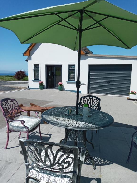 una mesa con una sombrilla verde en el patio en Luxury holiday rental with sea views on the Wild Atlantic Way en Tralee