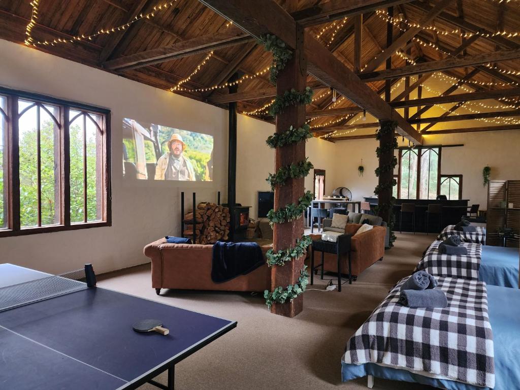 DAYLESFORD Frog Hollow Estate THE BARN - Wanting a different experience - Stay in the Barn - Table Tennis Table - Cinema Projector - Bar - Wood Fireplace - 3 QUEEN BEDS - A fun place for everyone في ديلسفورد: غرفة بها كنب وطاولة بينج بونغ
