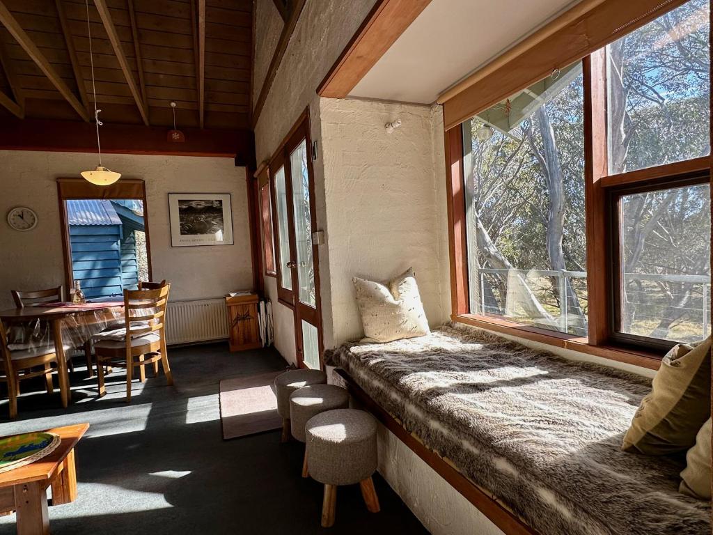 a room with a bed and a dining room with a table at Snow Gums 16, alpine-getaways in Dinner Plain