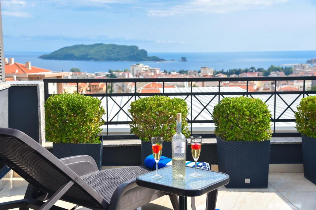 a table with two glasses of wine on a balcony at Misisuone Apartments Budva in Budva