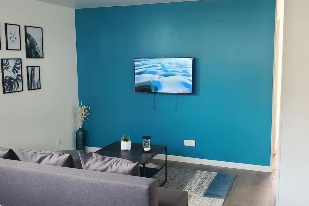 sala de estar con sofá y pared azul en Tulsa Home - Appartement 2 chambres, Charmant et moderne avec terrasse privée en Osny